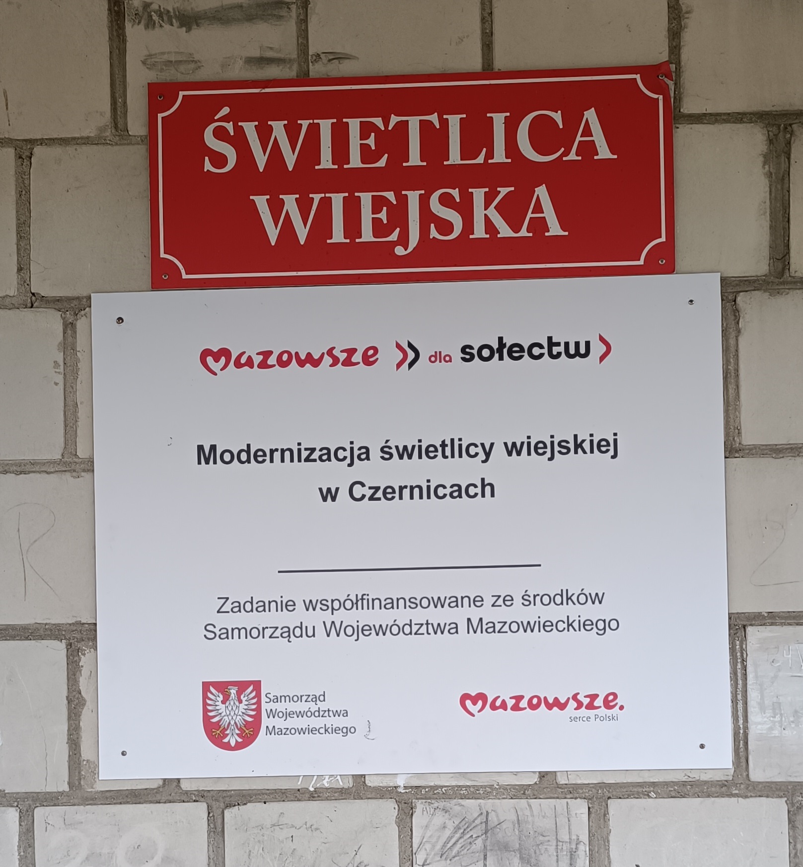 Zdjęcie przedstawia tablicę informacyjną o dofinasowaniu zadania ze środków budżetu Województwa Mazowieckiego